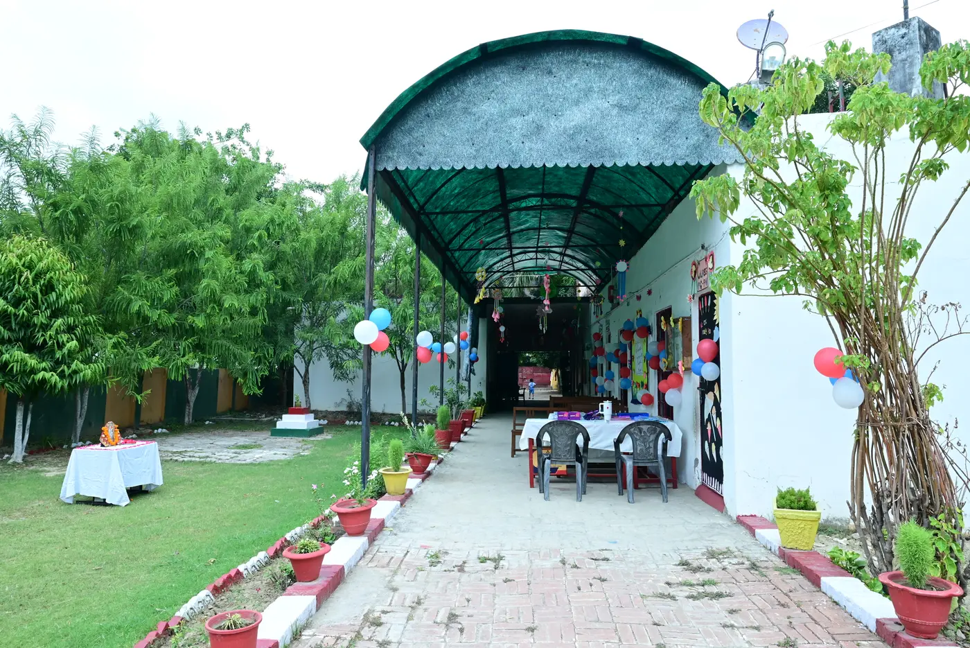 The covered walkway at Lords Public School under its green canopy, seen from the garden.